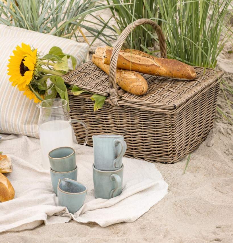 Bild av avkopplande picknick vid stranden med solros