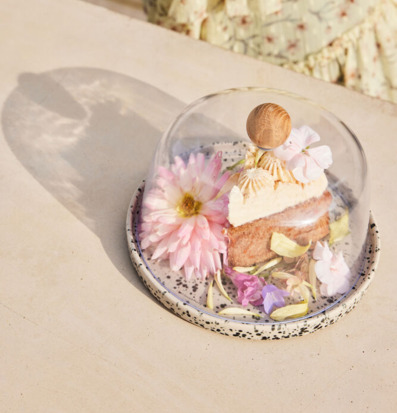 Bild av stilren ostkupa med dessert och blommor