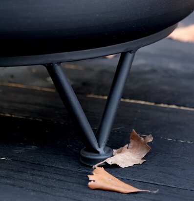 Bild av svart eldstad med dekorativ design och höstlöv