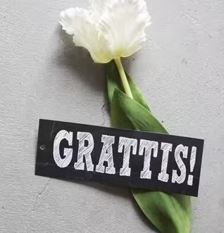 Bild av vit tulpan och etikett med Grattis-budskap
