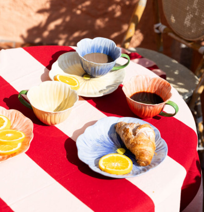 Bild av solig frukost med färgglada koppar och croissant