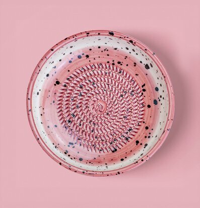 Bild av körsbärsrosa keramisk rivplatta med spiralmönster