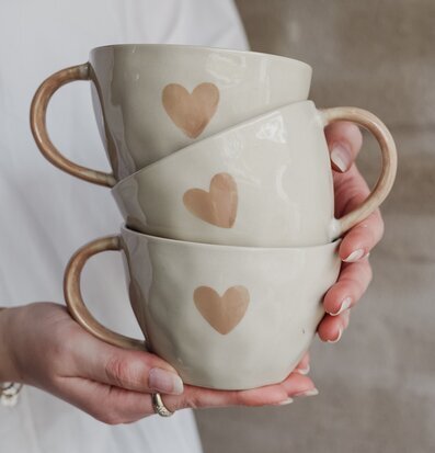 Bild av tre stilrena koppar med hjärtmotiv och keramik