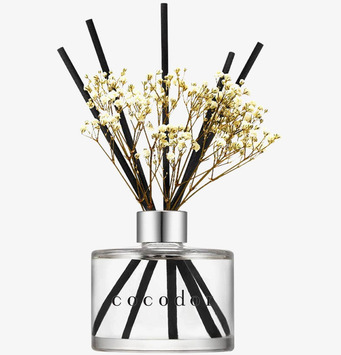 Bild av stilren glasflaska med doftpinnar och blommor