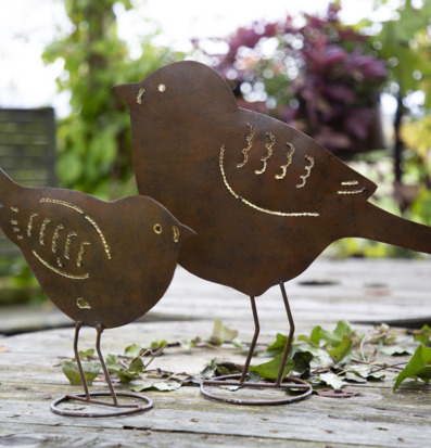 Bild av konstnärliga fåglar i hamrad plåt och grönska