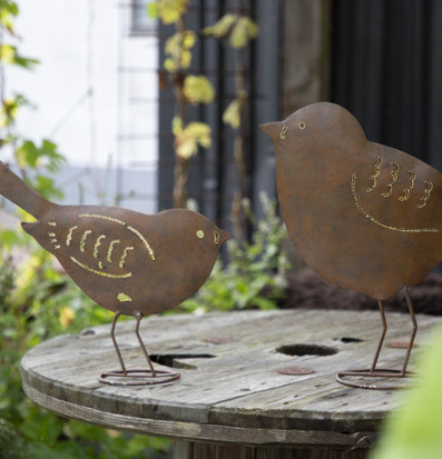 Bild av dekorativa fåglar på rustikt träbord i trädgård