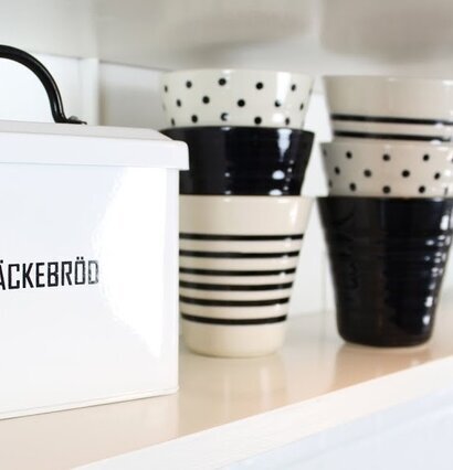 Lattemugg Prick Svart från Strömshaga på kökshylla med växt