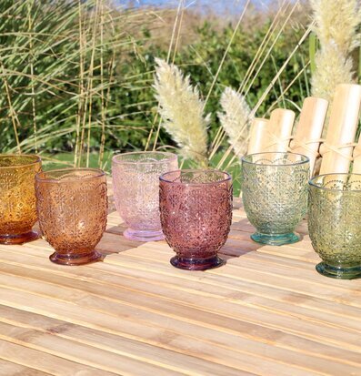 Bild av sex glas med intrikata reliefmönster i olika färger