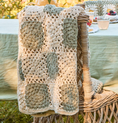 Bild av mysig utemiljö med virkad pläd och rottingstol