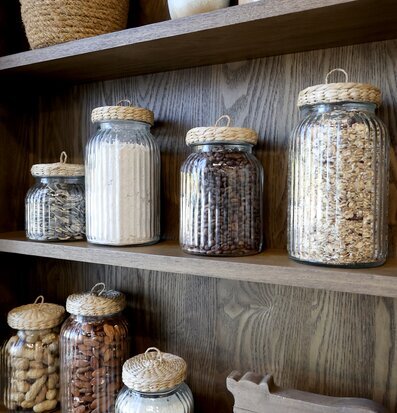 Bild av stilrena glasburkar på trähylla med växt och koppar