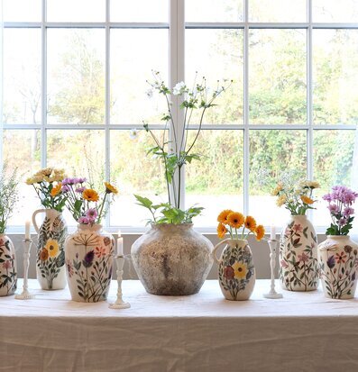 Bild av dekorativa kannor och blommor i naturligt ljus