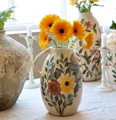 Bild av lantlig interiör med kanna och blomstermotiv