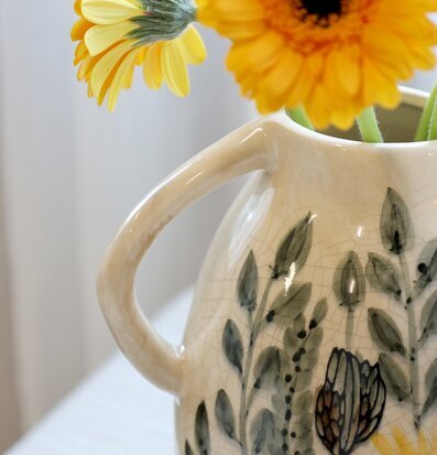 Bild av dekorativ kanna med blommotiv och antik känsla