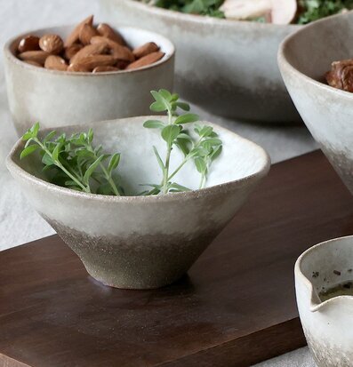 Bild av rustika skålar med örter och nötter i fokus