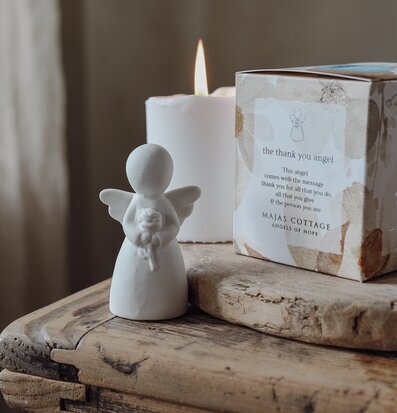 Bild av änglastaty och stearinljus på rustikt träbord