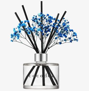 Bild av doftpinnar i glasbehållare med blå blommor