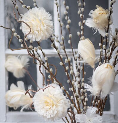 Bild av konstgjorda vårkvistar och fjädrar i vaniljtoner