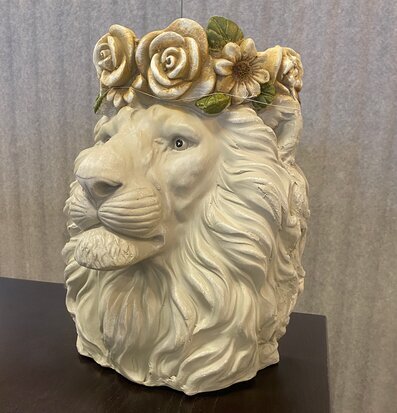 Foto av en lejonformad kruka med blomkrans och detaljer