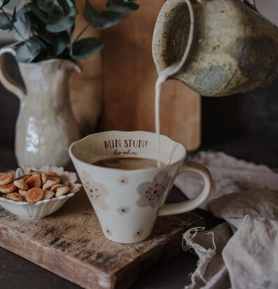 Foto av hemtrevlig scen med mugg och kex i fokus