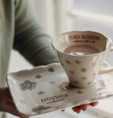 Bild av dekorativ kopp och fat med blommönster och text