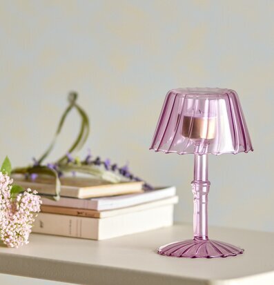 Bild av elegant ljusstake i rosa glas med böcker