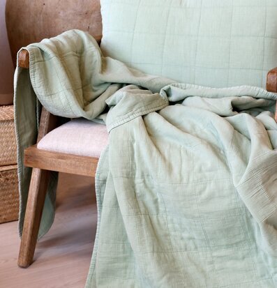 Bild av inbjudande interiör med grön pläd och rottingstol