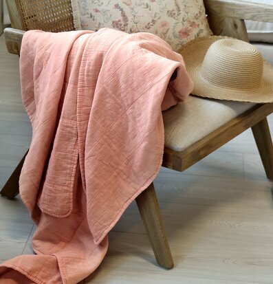 Bild av mysig interiördetalj med rosa pläd och stol