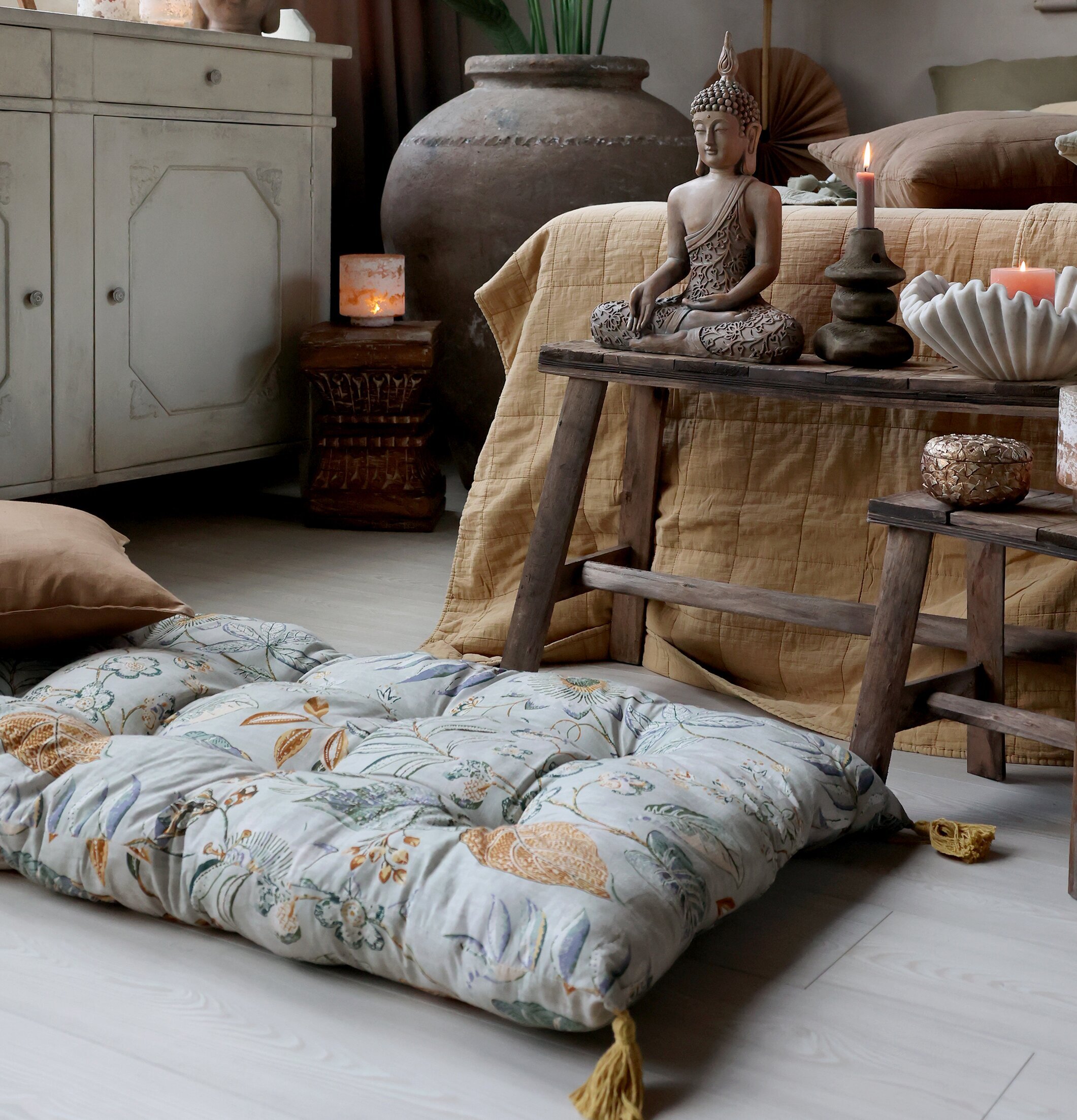 Bild av harmoniskt rum med golvmadrass och Buddha-statyer