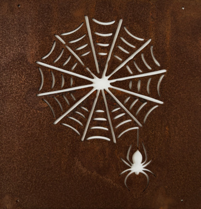 Bild av intrikat spindelnät i rostbrun metallplatta