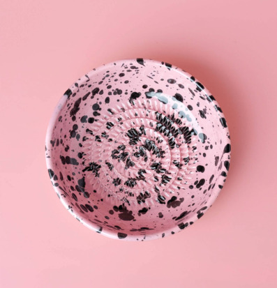 Bild av keramisk rivplatta i rosa med svarta stänk och taggar