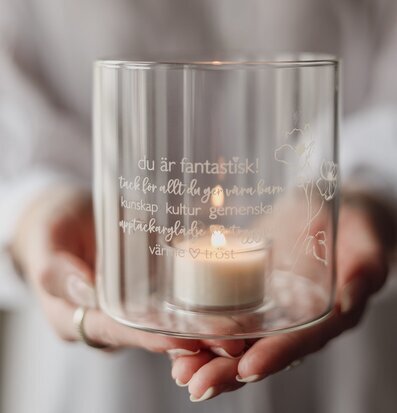 Bild av ljuslykta i glas med tacksamhetsbudskap och blommor