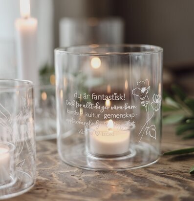 Bild av cylinderformad ljuslykta med gravyr och blommor