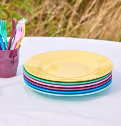 Bild av färgglada tallrikar och plastbestick utomhusdukning