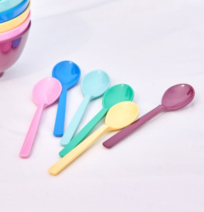 Bild av färgglada teskedar i melamin på vit duk utomhus