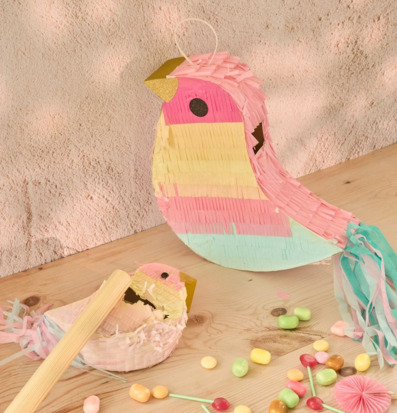 Bild av färgglad fågelpiñata och godis på ljust träbord