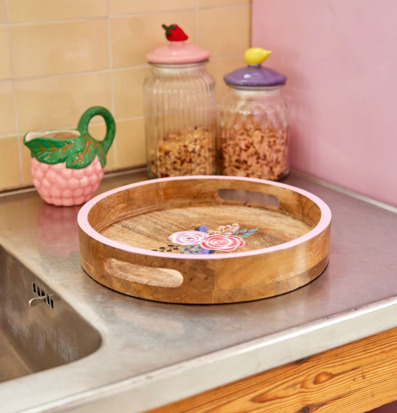 Bild av rund träbricka med handmålade blommor i köksmiljö