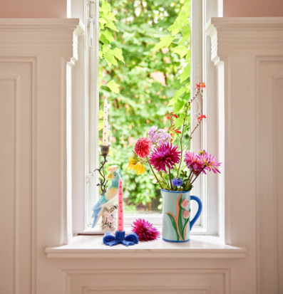 Bild på färgstarkt fönsterarrangemang med keramik och blommor