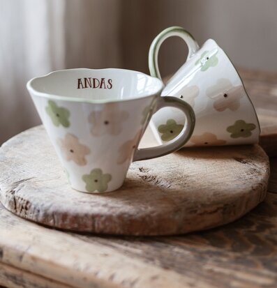 Bild på två mönstrade keramikkoppar på rustik träbricka