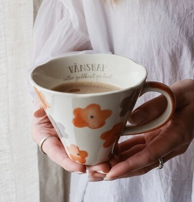 Bild på handmålad blommig mugg med kaffe och varm atmosfär