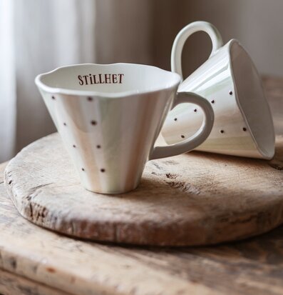 Foto av handgjorda keramikkoppar på träfat i mjukt dagsljus