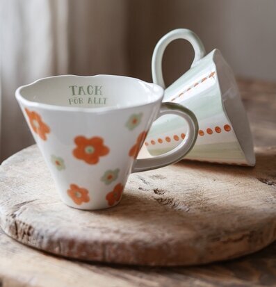 Bild av två keramikkoppar med blommönster på träbricka