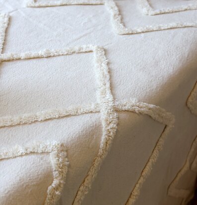 Bild av bäddad säng med offwhite överkast och texturerade kuddar