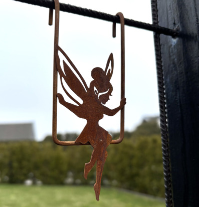 Bild av rostig älva på gunga – trädgårdsdekoration i metall