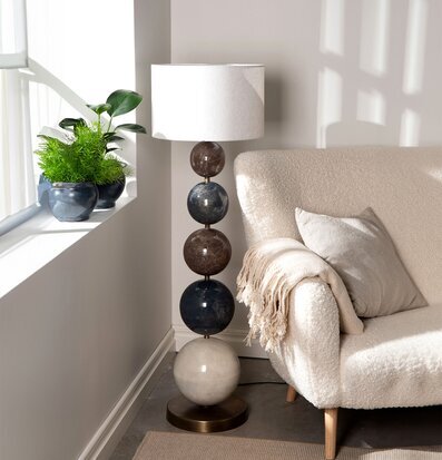 Bild på harmonisk vardagsrumshörna med modern lampfot och soffa