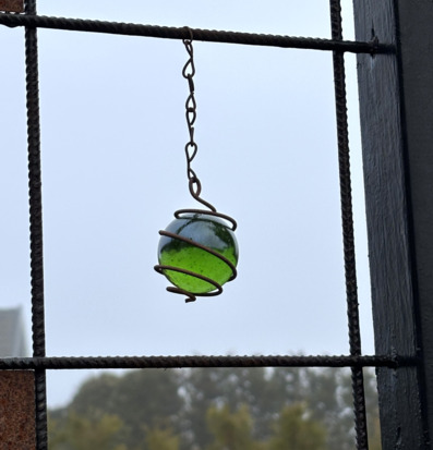 Bild av hängande grön glaskula i armeringsnät utomhus