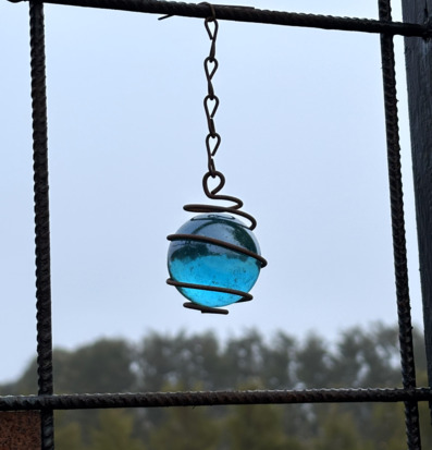 Bild på blå hängande glaskula i armeringsnät utomhus