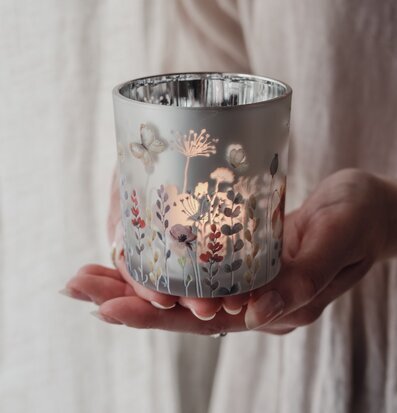 Bild på hand som håller dekorativ glaslykta med blommotiv