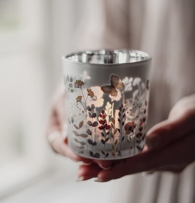 Bild av hand som håller dekorativ glaslykta med blommotiv