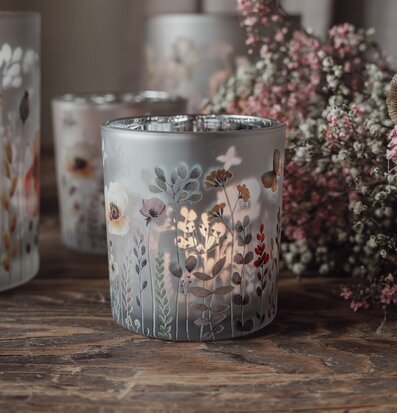 Bild av ljuslykta med växtmotiv och torkade blommor på bord