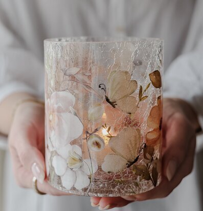 Bild av glaslykta med blommor och fjärilar i närbild